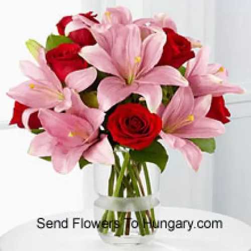 Rote Rosen und rosa Lilien mit saisonalen Füllstoffen in einer Glasvase