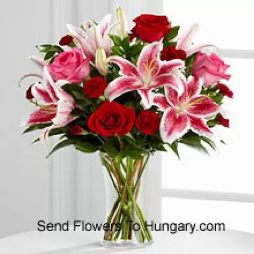Красные и розовые розы с розовыми лилиями и сезонными наполнителями в стеклянной вазе